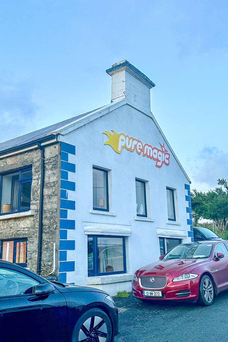 The outside view of the white building that is Pure Magic with a chimney at the top.