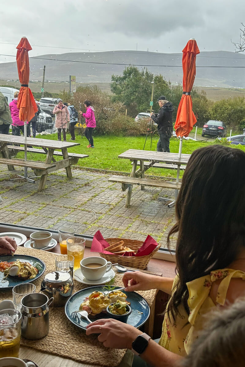 A view out the window at breakfast of the Boyne Nordic Walking group setting out on their trek with picnic tables and red sun umbrellas.
