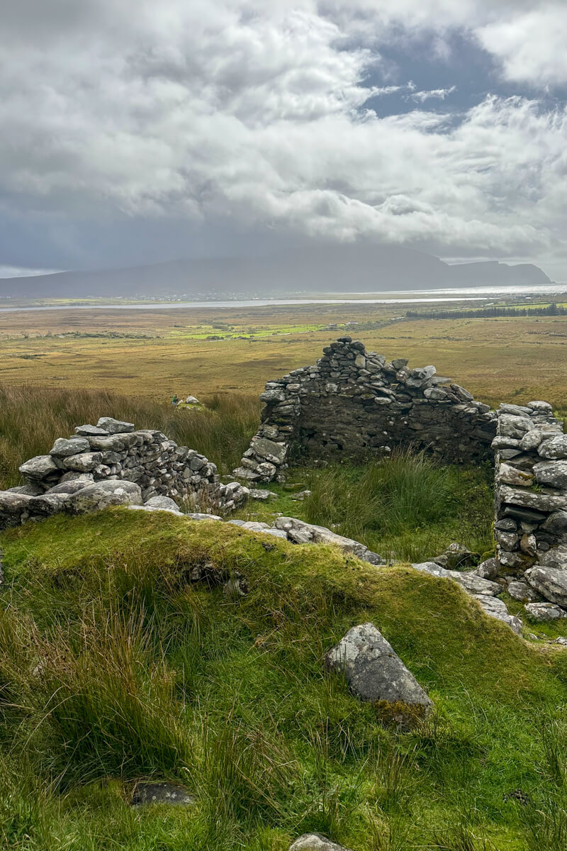 Deserted village stone ruins on Achill Island, County Mayo, Ireland with sun shining down