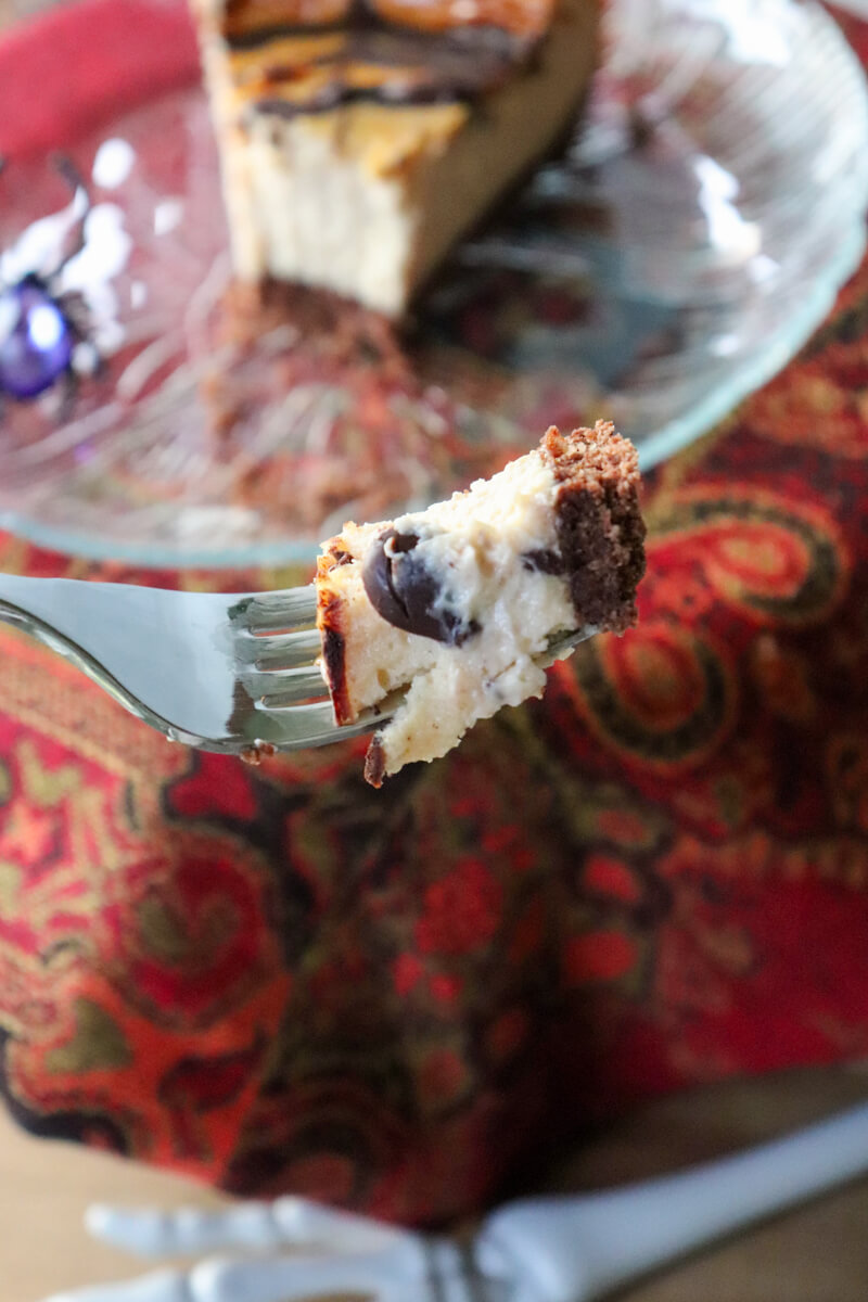 A bite of low carb Halloween cheesecake on a fork in front of a plate with the rest of the piece.