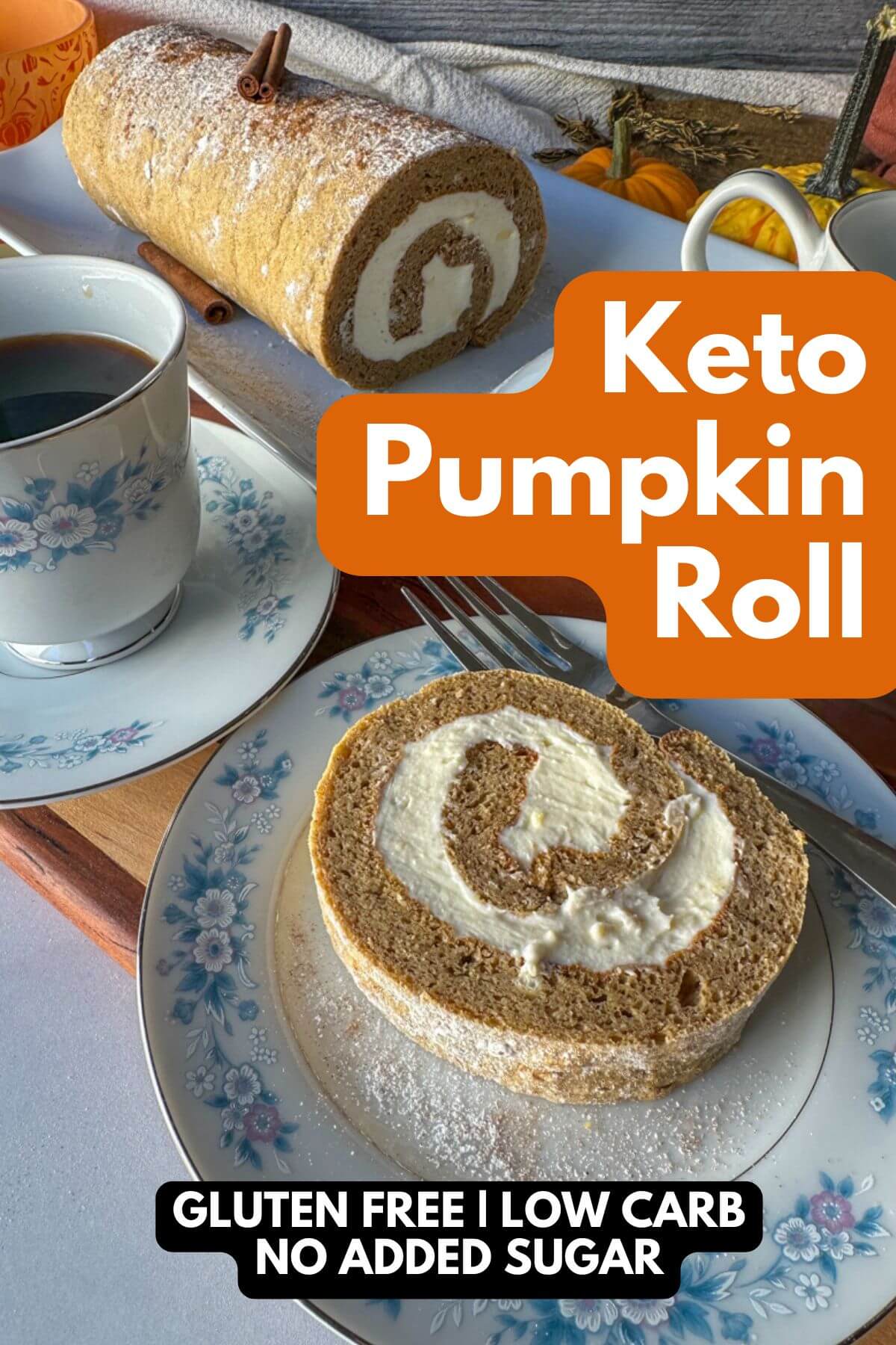 Slice of keto pumpkin roll with creamy swirl on a floral china plate, with the rest of the roll in the background on a wooden cutting board. Text overlay: “Keto Pumpkin Roll – Low Carb, Sugar Free, Gluten Free.”