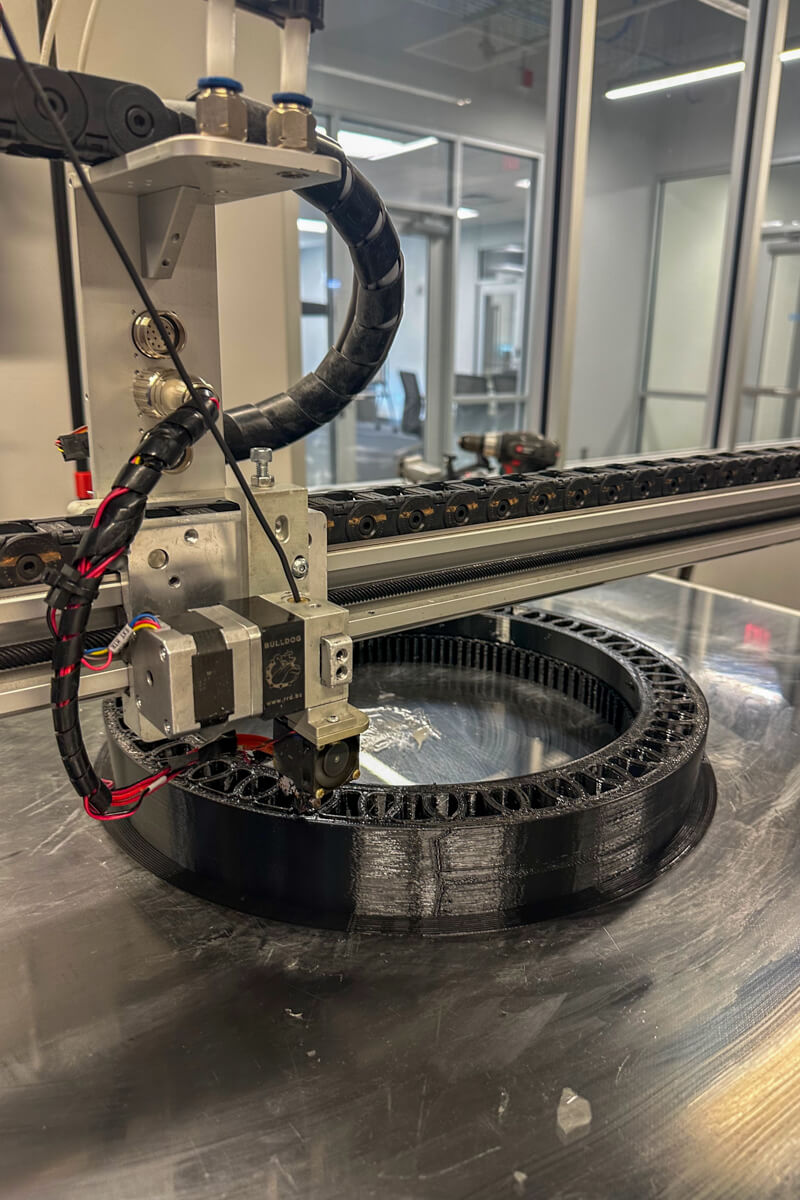 A 3D printer printing a black circular part