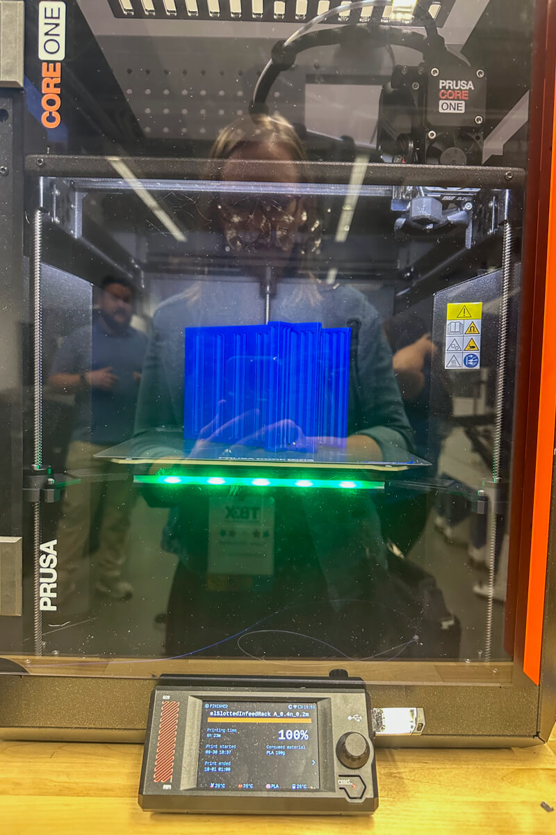A front view of a 3D printer printing a blue part