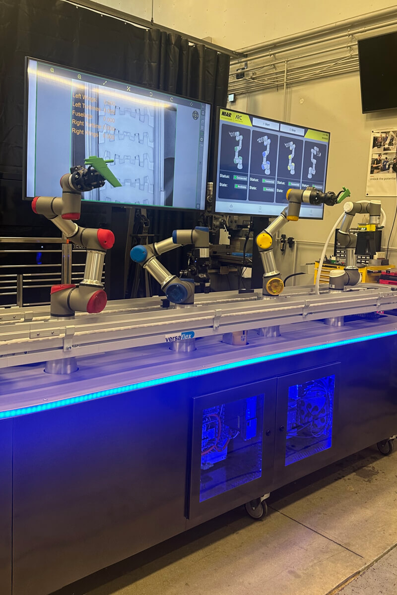 A lineup of three robotic arms next to a conveyor belt