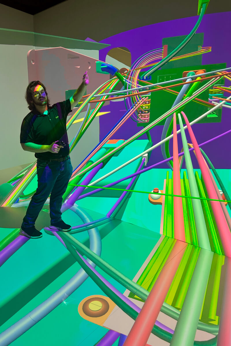 A current student demonstrating the training program to replace a part in the airplane with the colored screen on the wall