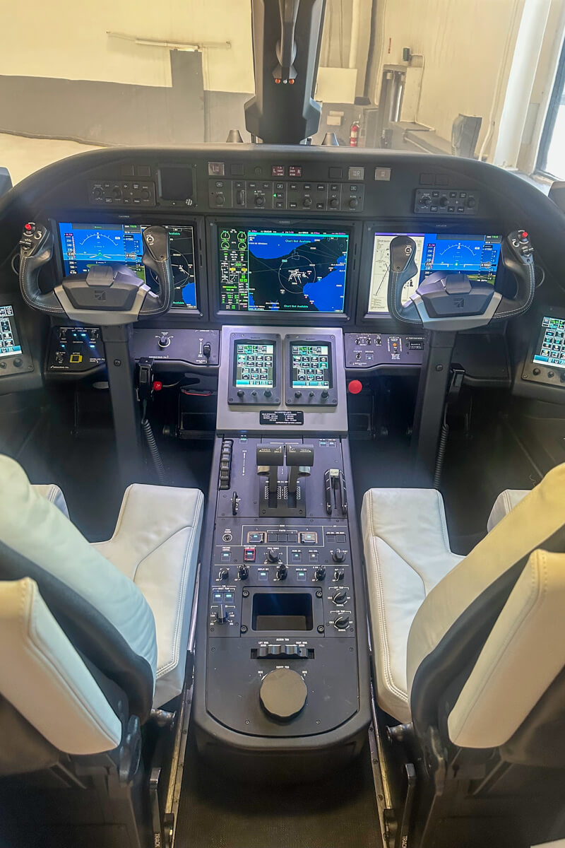 Cockpit inside view with two controls, screens, buttons, etc. Also, two white seats