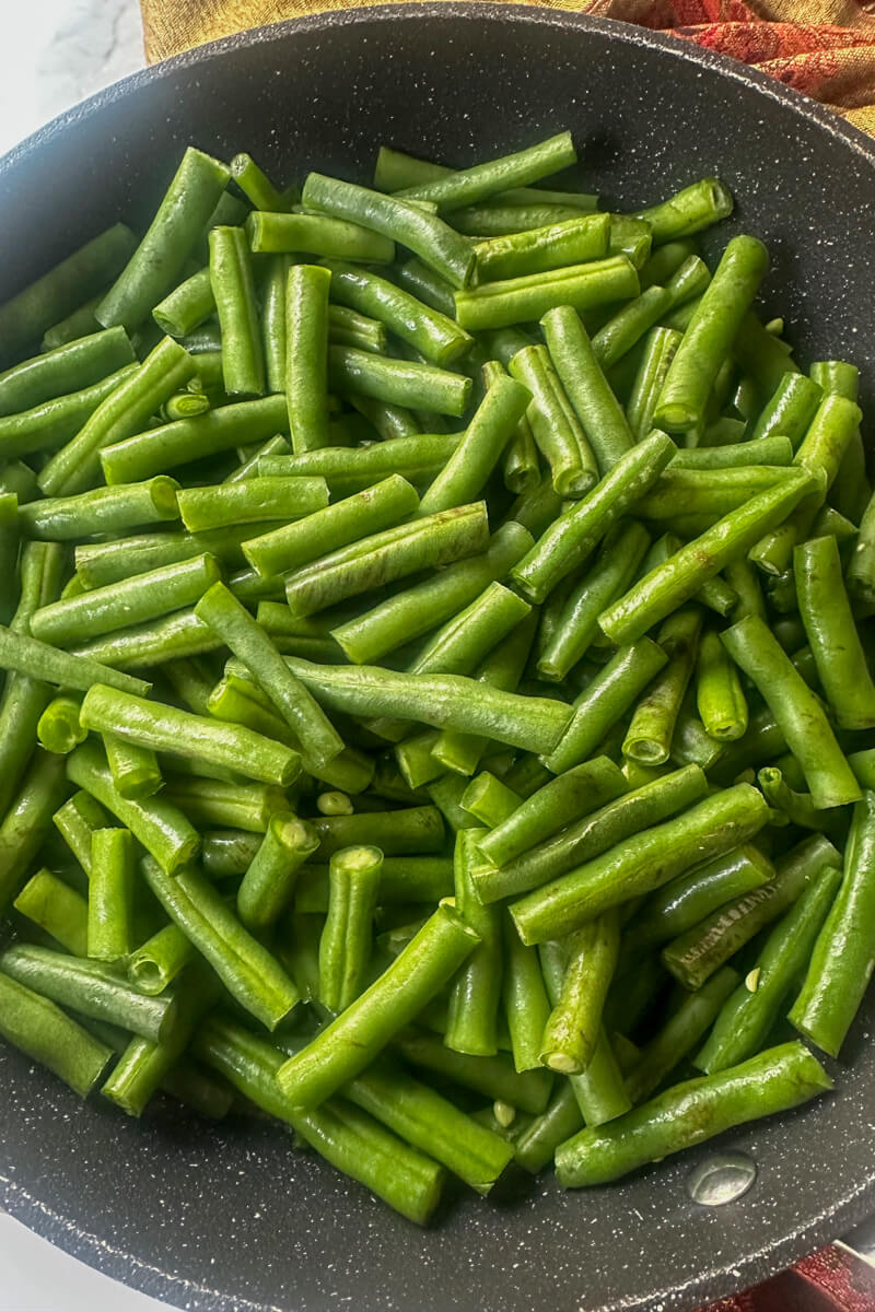 Overhead view of cut green beans in a black skillet
