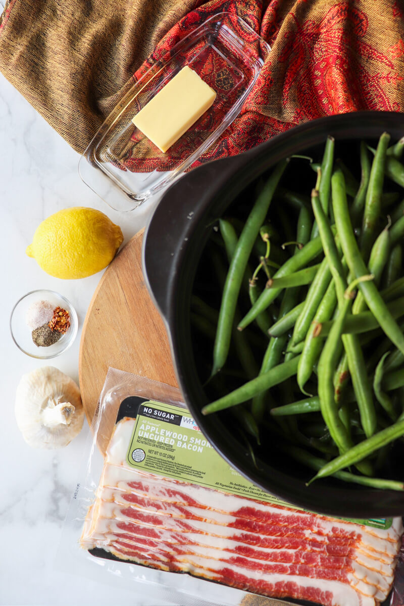 Overhead view of black bowl of green beans, ButcherBox bacon, butter, lemon, spices, etc.