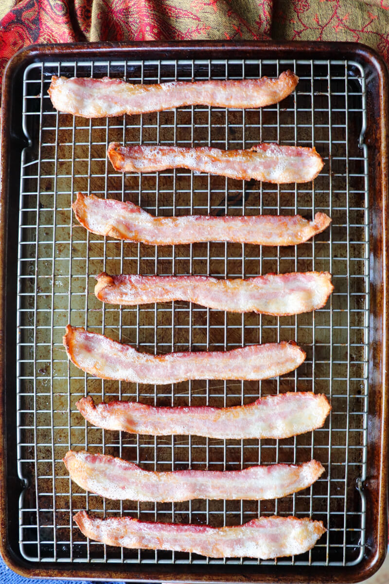 Overhead view of lined up bacon on a baking pan with grill