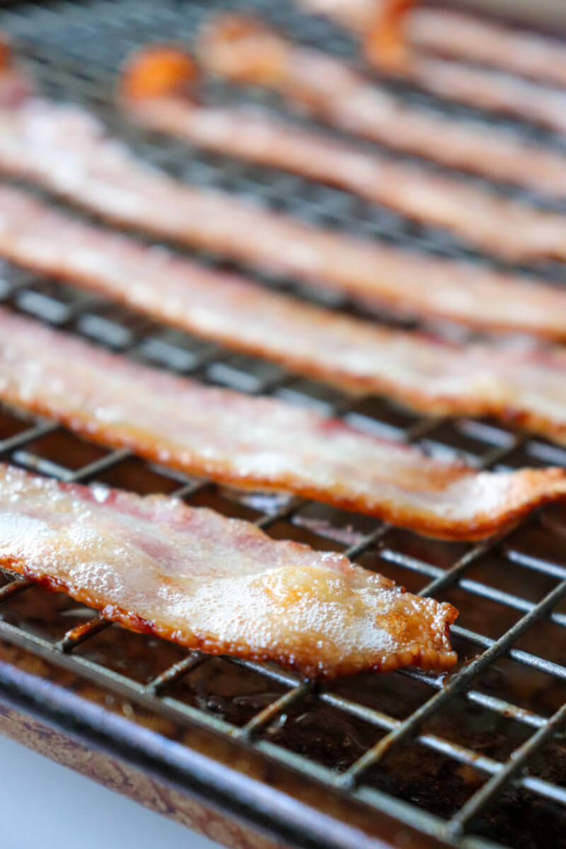 Front view lined up bacon on a baking pan with grill