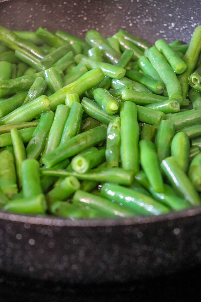 Close up of a black skillet with green beans