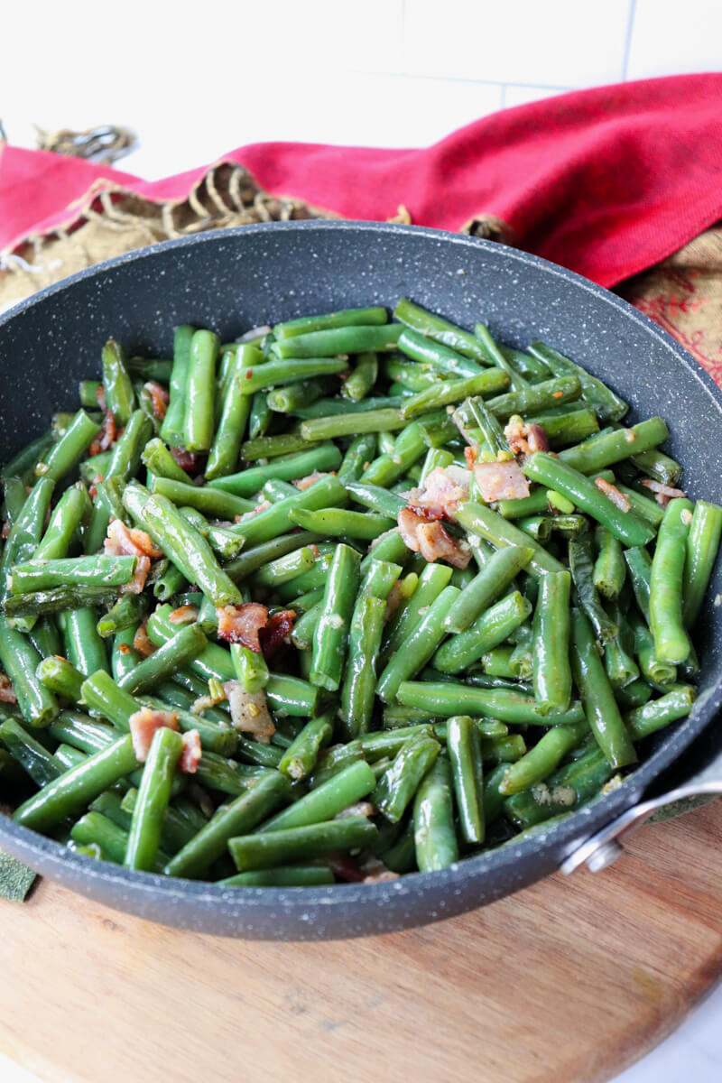 Black skillet of sauteed green beans and bacon