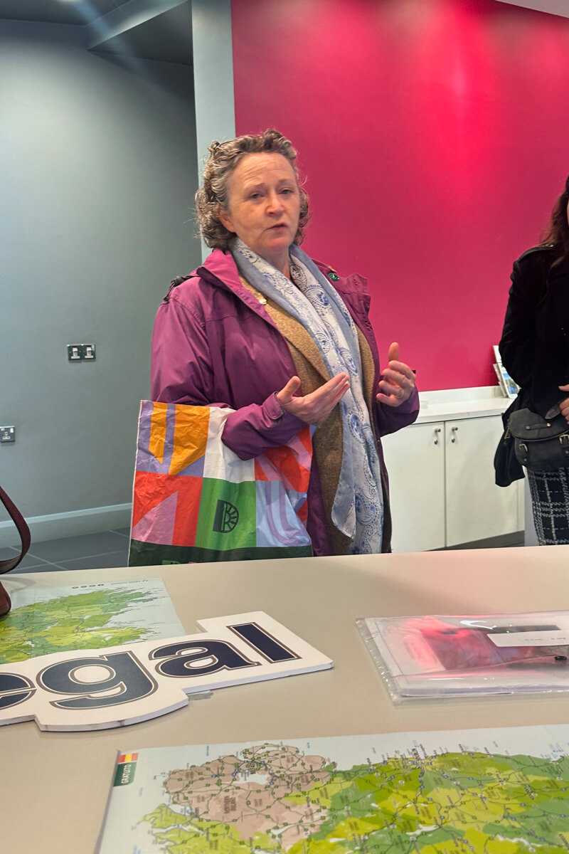 Naimh in a pink jacket and white print scarf speaking at the visitor center