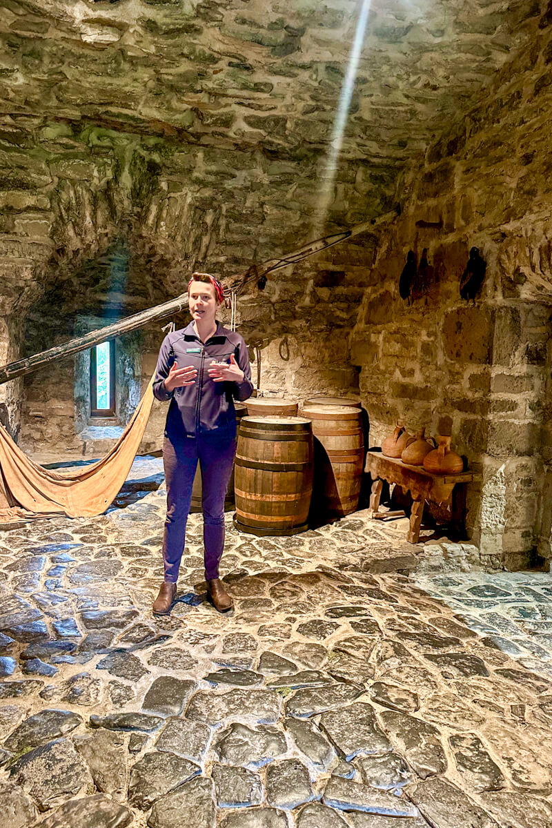 Emma in jeans and a navy jacket speaks in the original lower level of Donegal Castle