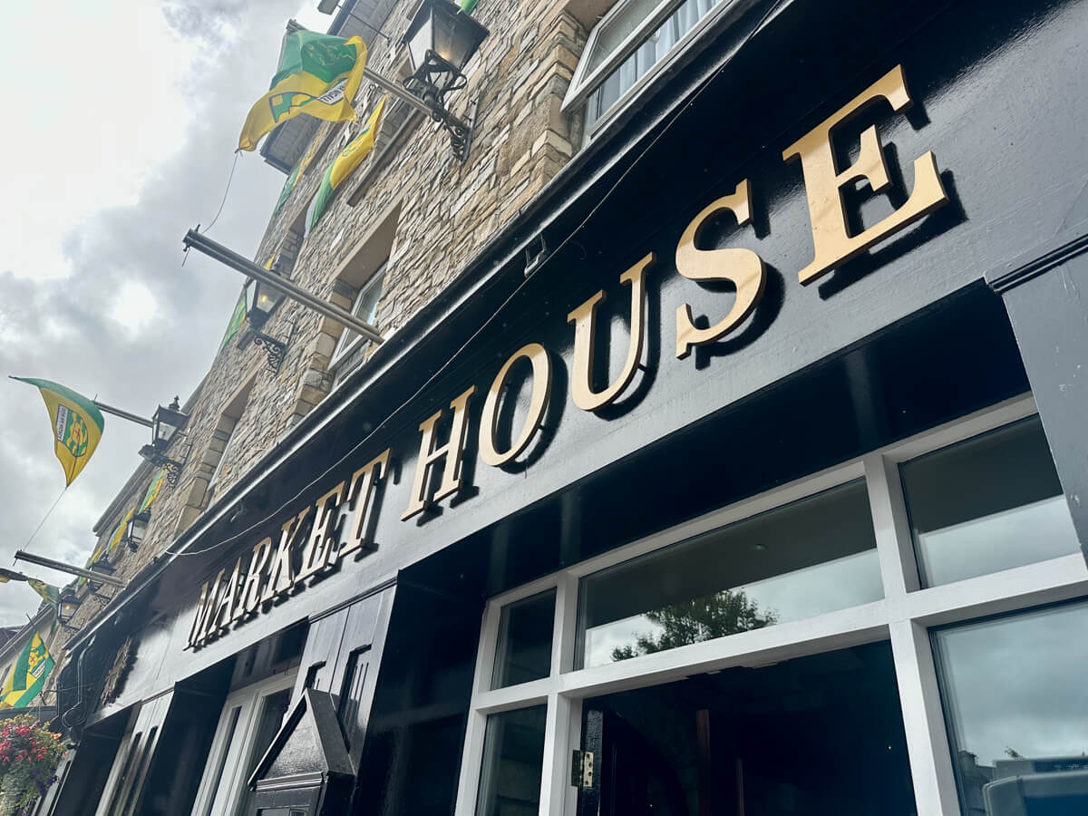 Outside front view of the Market House Restaurant with a yellow and green flag flying overhead