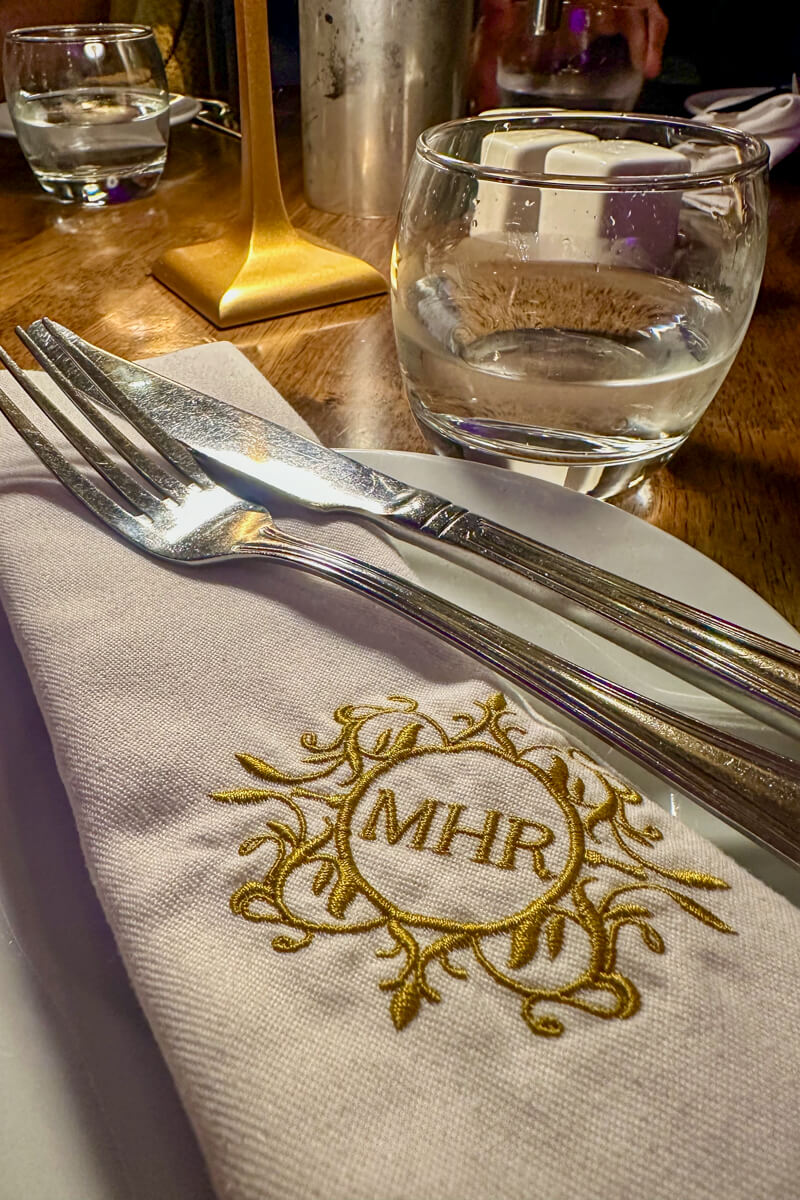 Market House logo (MHR) on a white napkin with silverware and a water glass