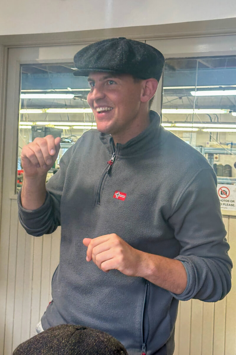 Owner John Patrick Hanna modeling a newsboy cap and speaking