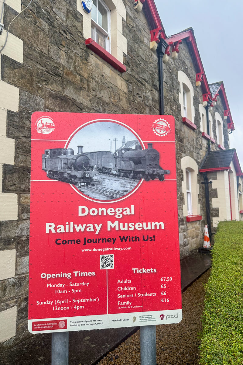 A red sign that says "Donegal Railway Museum" in front of the stone building