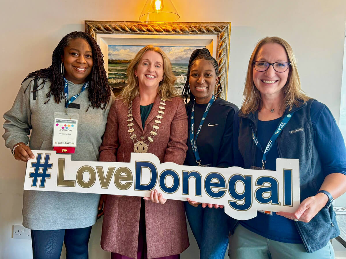 Four women holding a sign and smiling at the camera in the Quay Restaurant that says #LoveDonegal