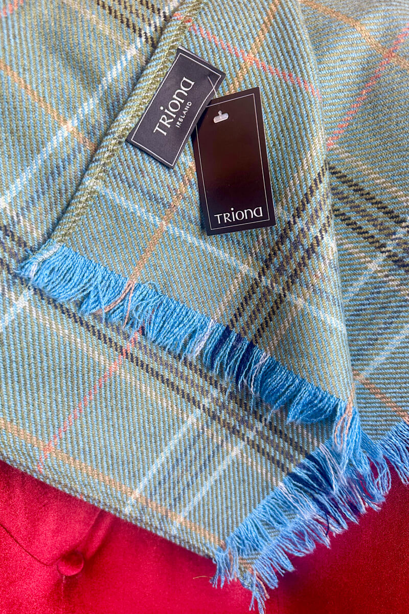 Green, blue, pink plaid Donegal tweed scarf with a black tag that says "Triona"