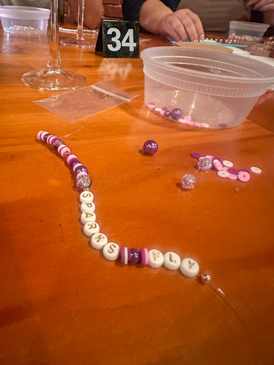 Purple beaded bracelet on a wooden table that says Sparks Fly