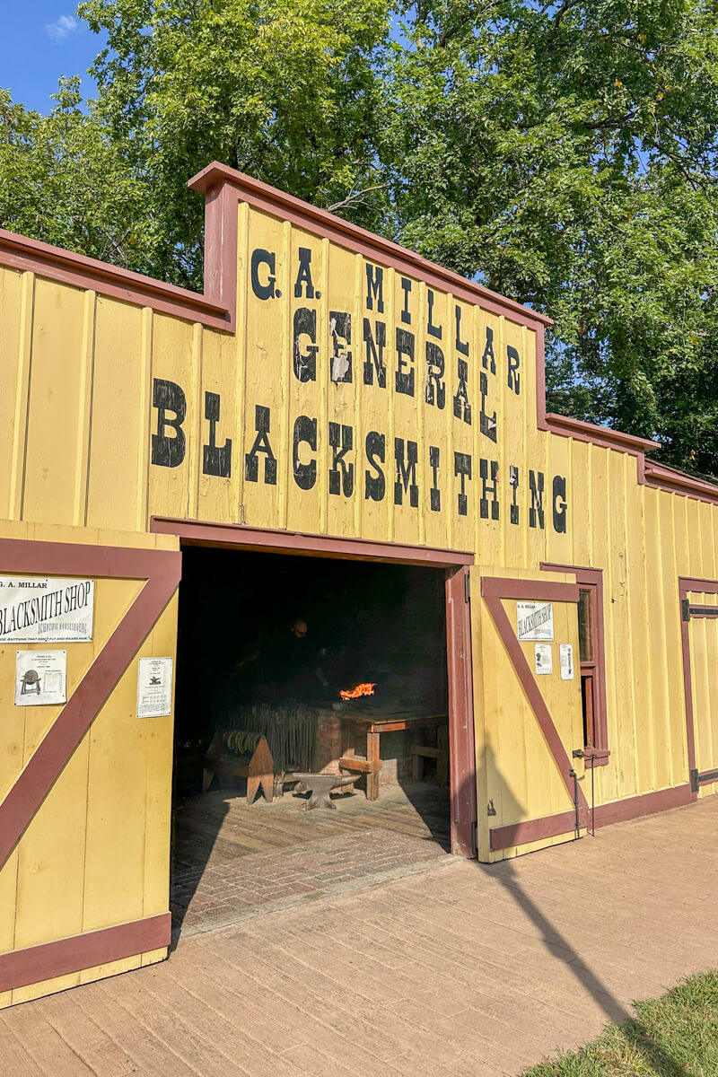 A yellow wooden building labeled "General Blacksmithing"