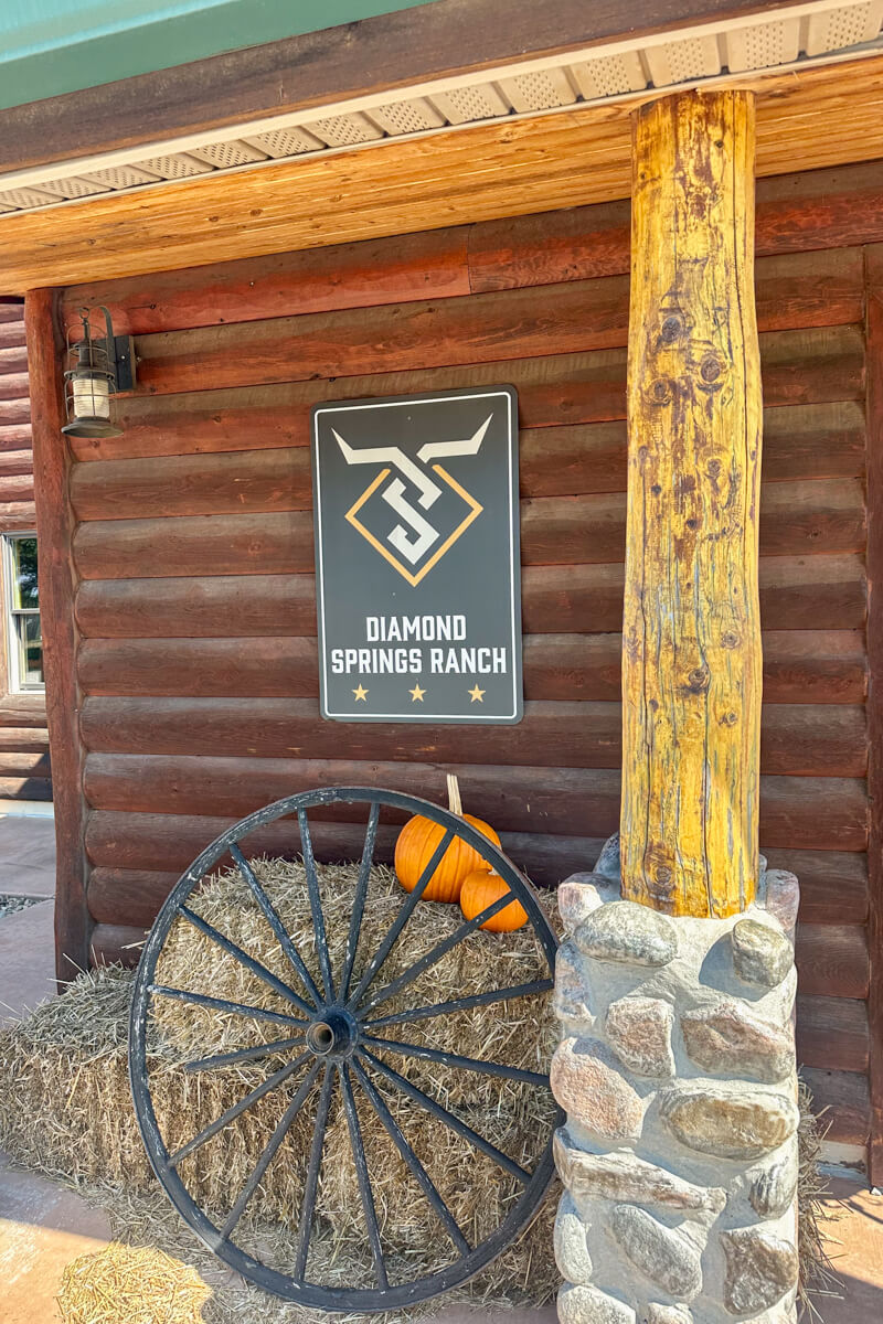 Front view of the Diamond Springs Ranch log building, a haybale with pumpkins.