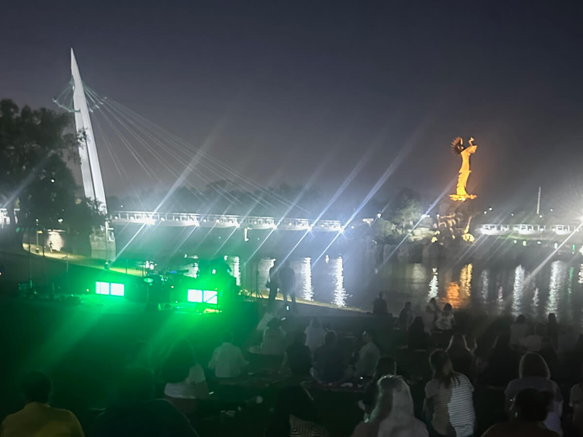 The Keeper of the Plains by night with fires lit and a view of the bridge