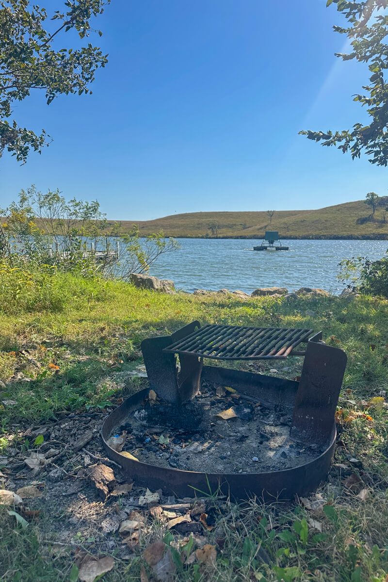 A campsite with grill with a view of Chase Lake in the background