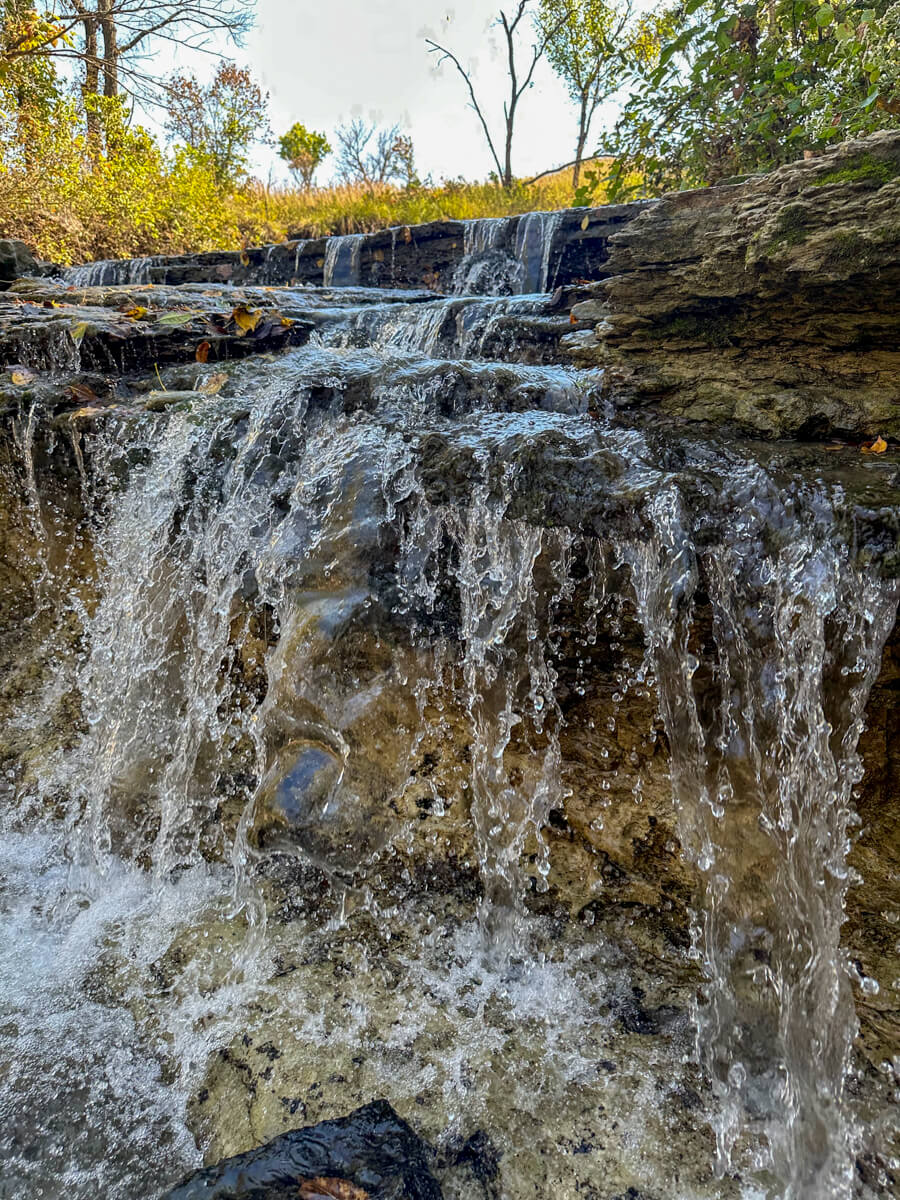A waterfall with trees and yellow green foliage in the background