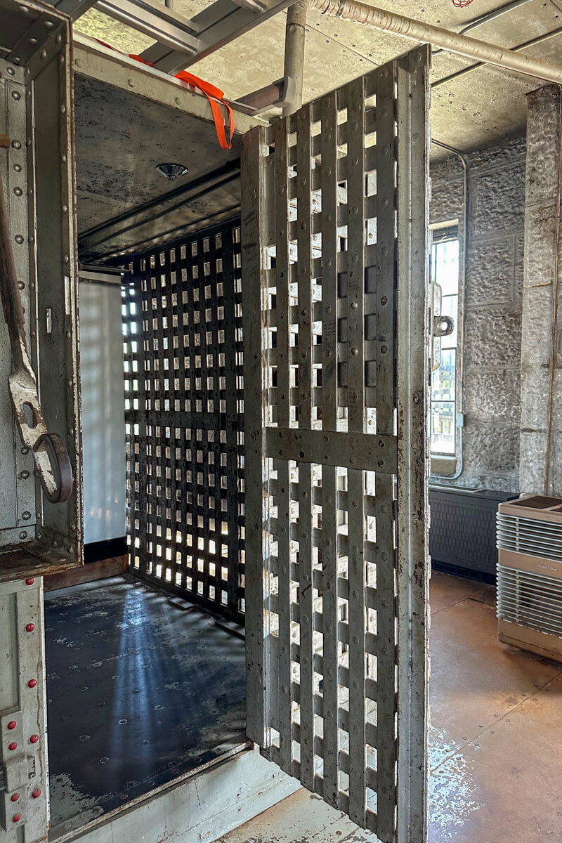 A view into the old jail at the courthouse with crossed bars and light from a window in the background