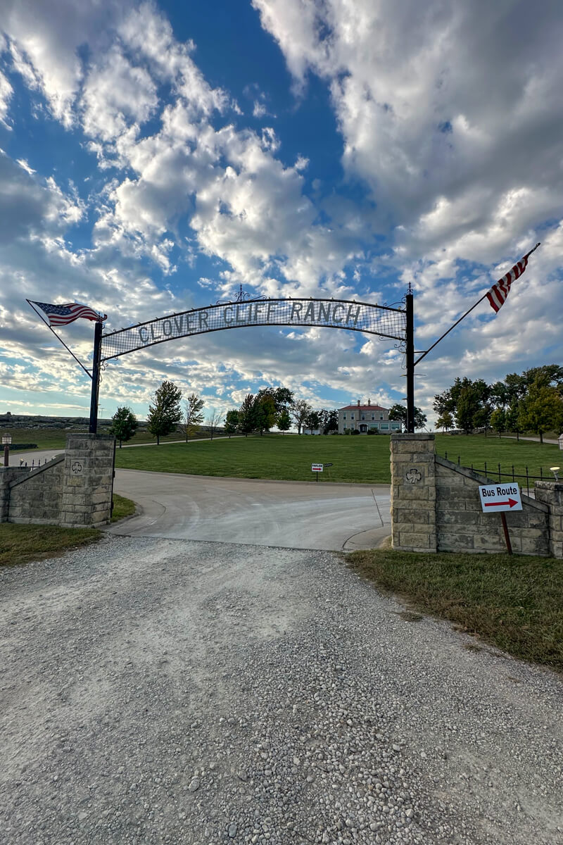 Metal sign over the driveway entrance that says "Clover Cliff Ranch"