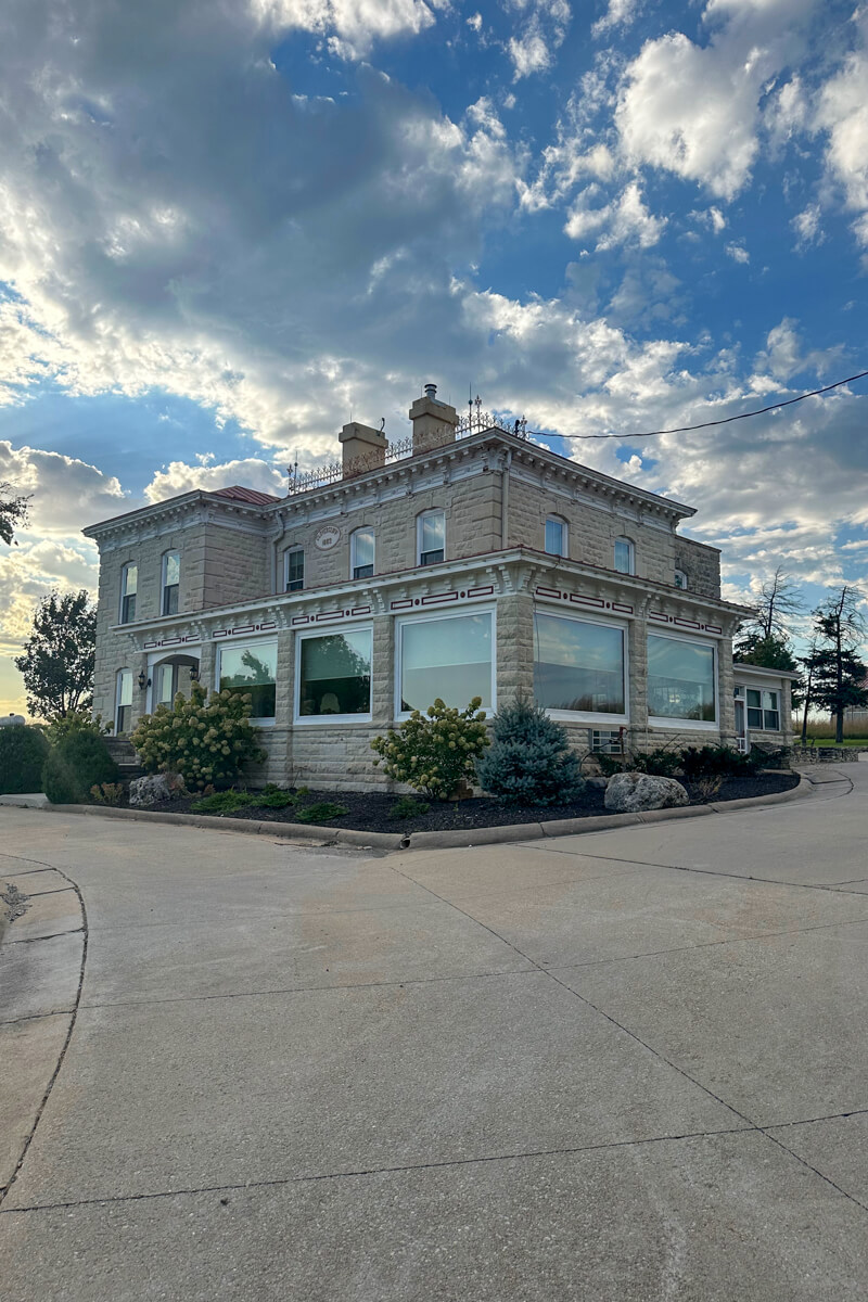 The light colored Clover Cliff Ranch building with clouds in the background