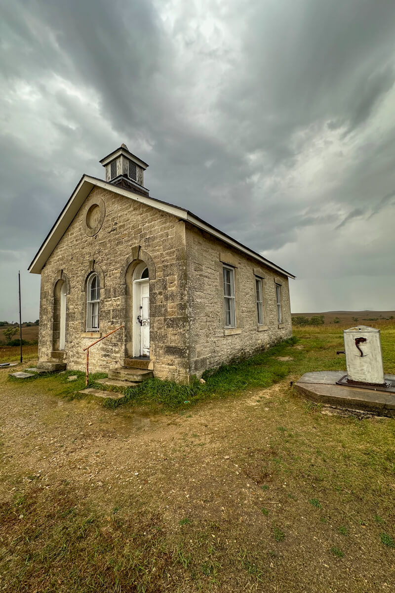 Looking up at the one room school house with the path around and clouds in the background