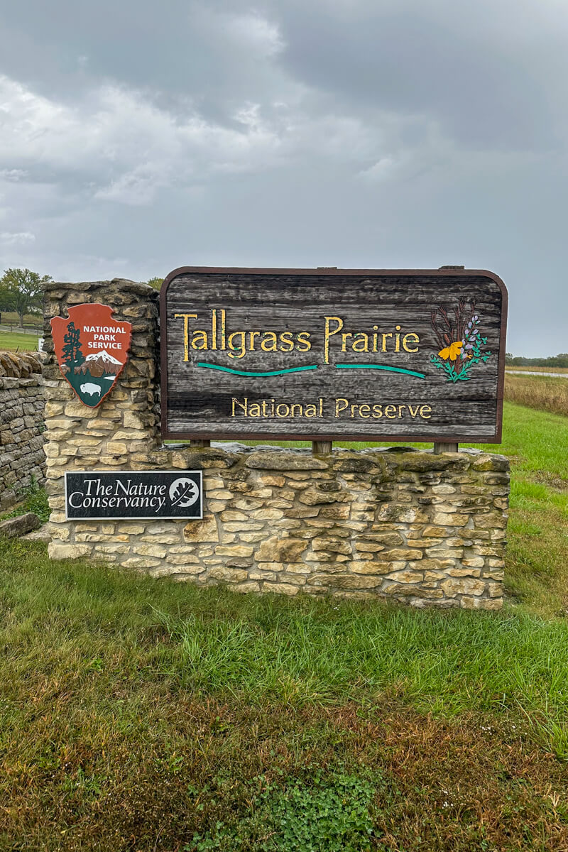 Tallgrass Prairie sign with the National Parks symbol on a small stone wall surrounded by grass