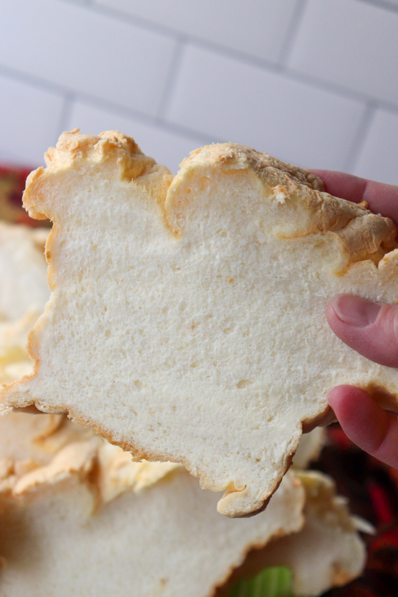 A hand holding up a piece of gluten free egg white protein bread