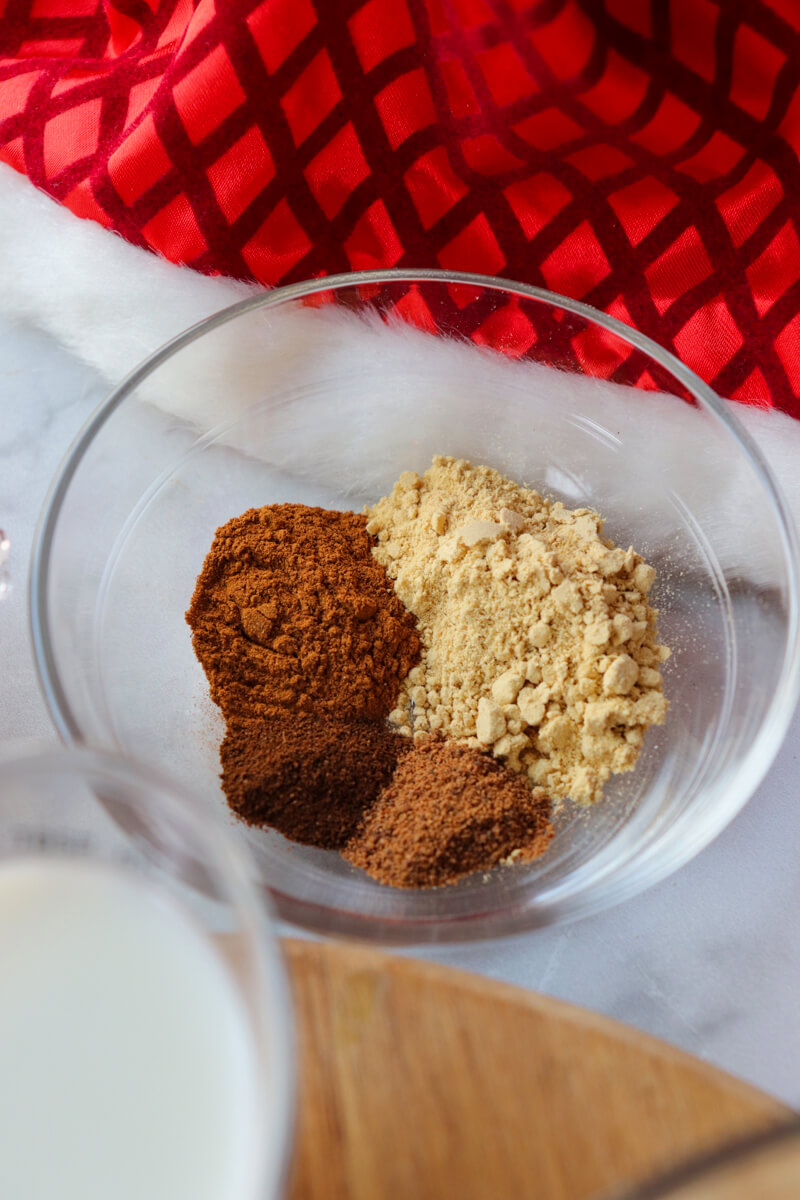 A glass bowl of the ground spices, ginger, cloves, nutmeg, and cinnamon