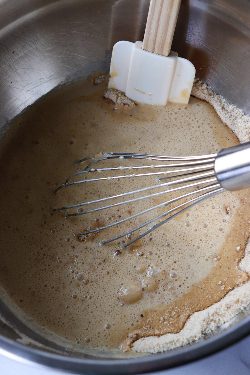 A metal bowl with a whisk stirring the keto gingerbread muffin batter