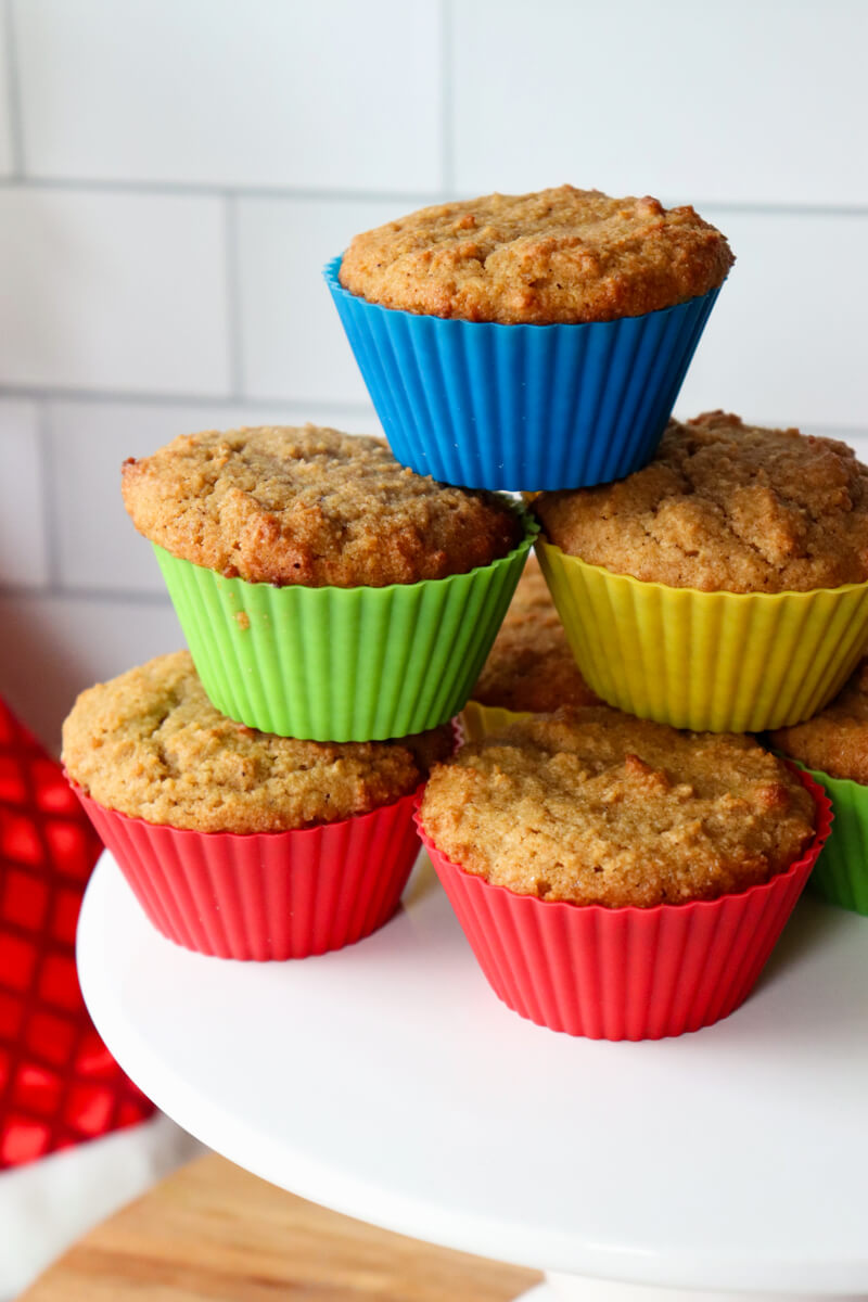 A stack of keto gingerbread muffins in colored silicone cups. On a white pedestal