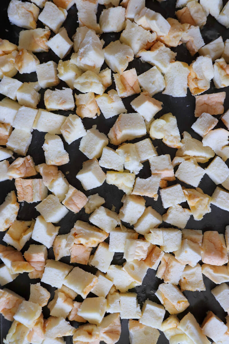 Overhead view of a baking sheet with untoasted cubed white gluten free protein bread