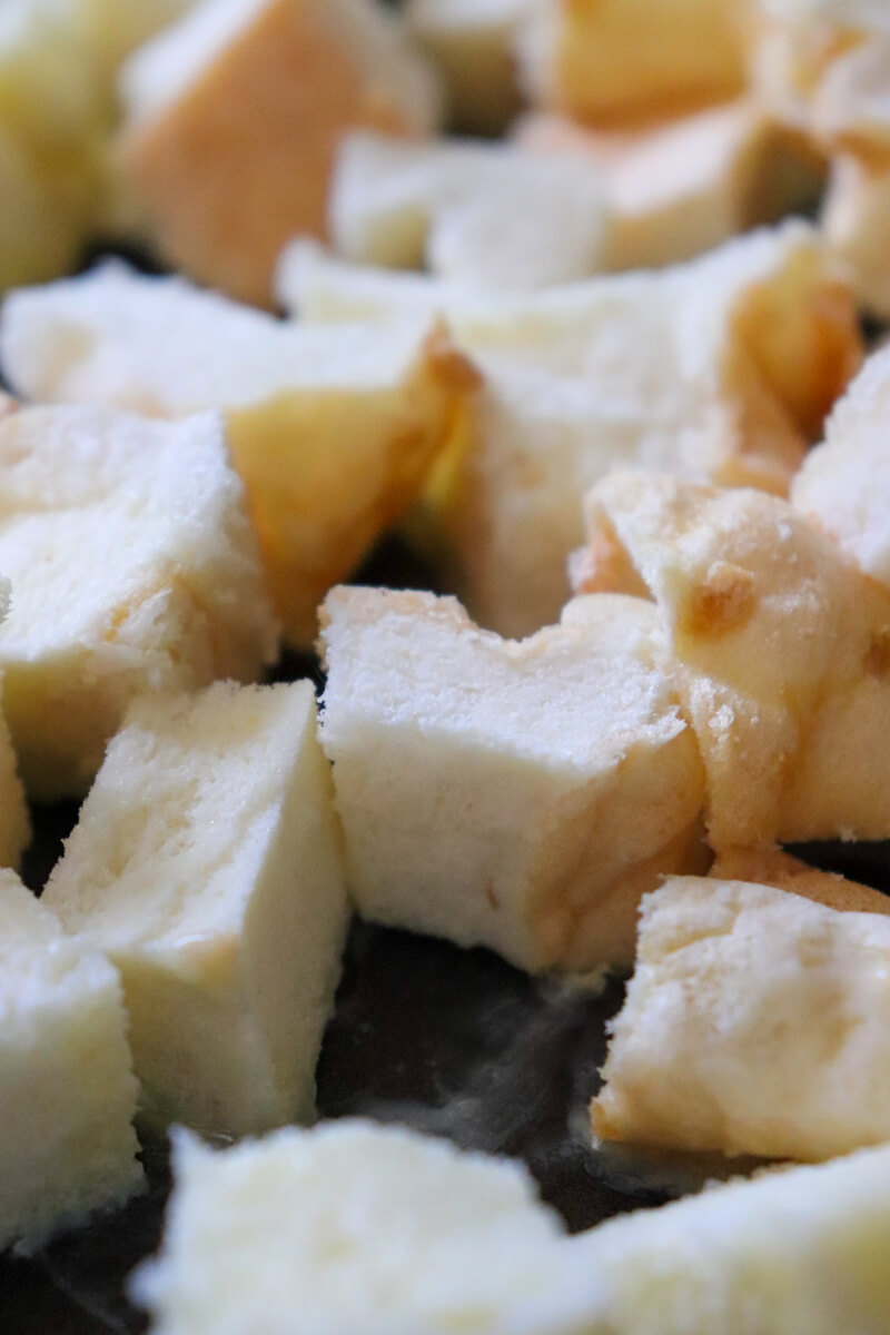 Front close up view of a baking sheet with untoasted cubed white gluten free protein bread