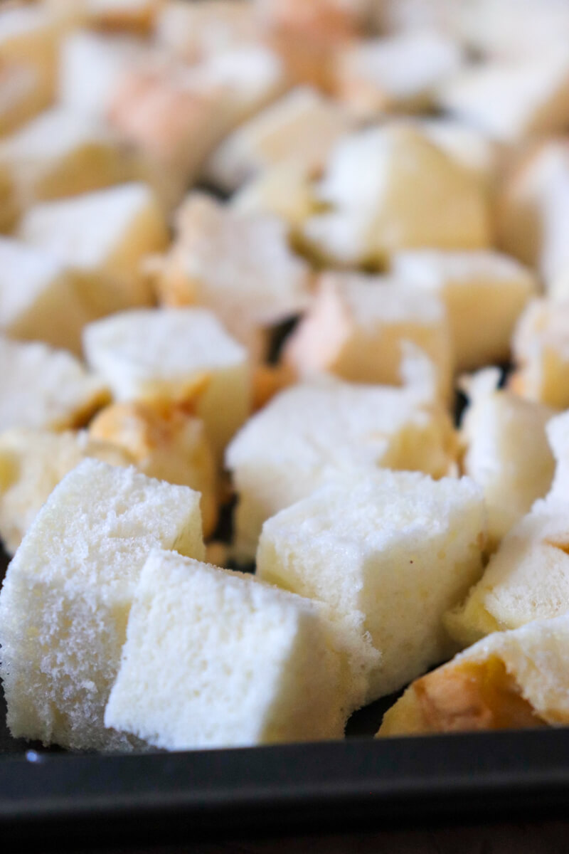 Front close up view of a baking sheet with untoasted cubed white gluten free protein bread