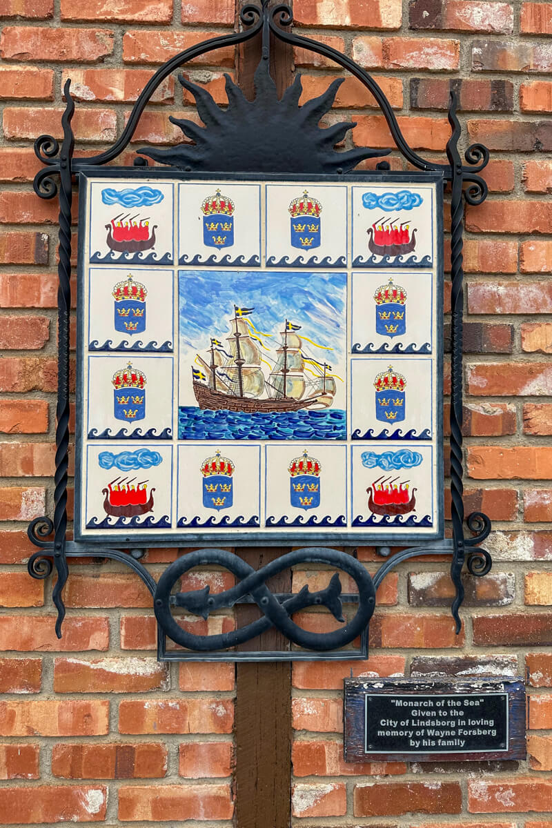 An iron sign on a brick wall with a boat picture