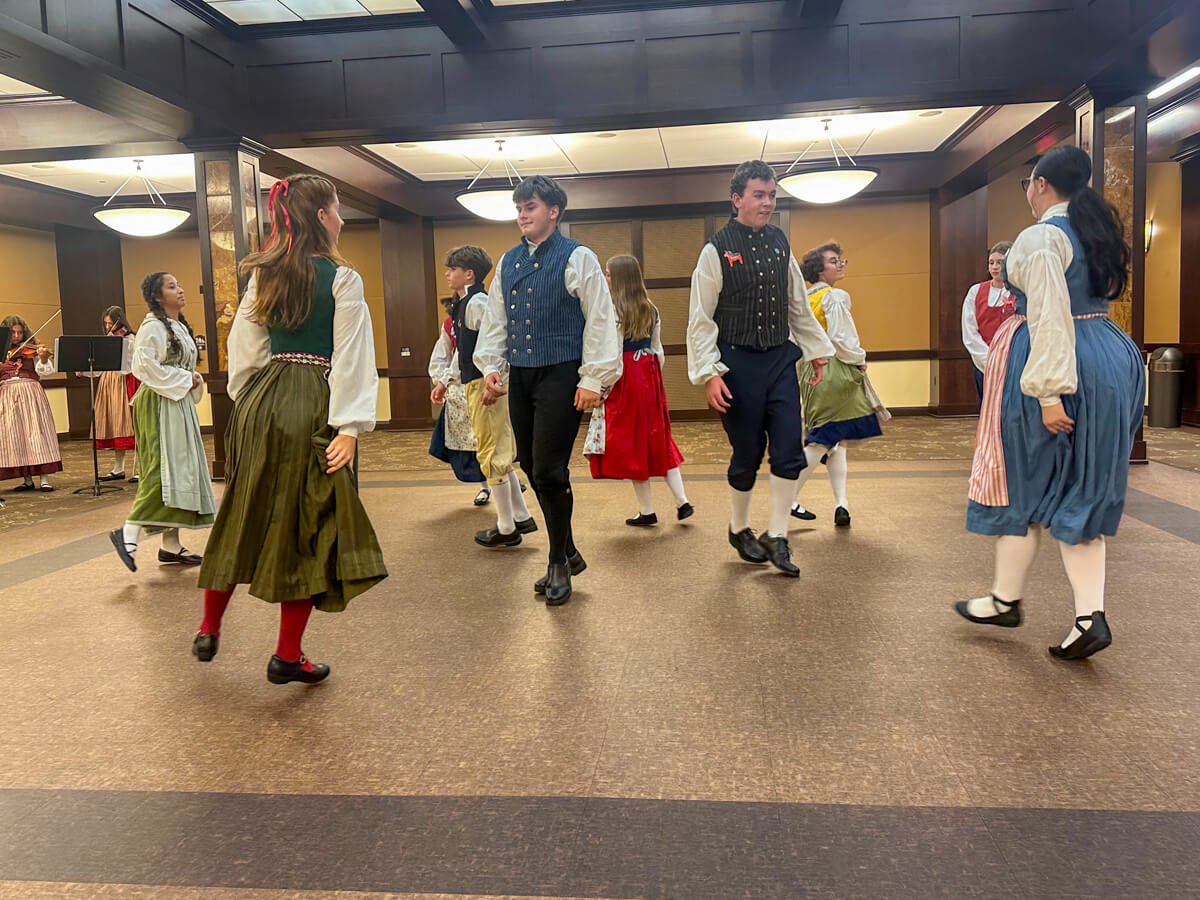 Swedish traditional dancers in costume and musicians in the corner