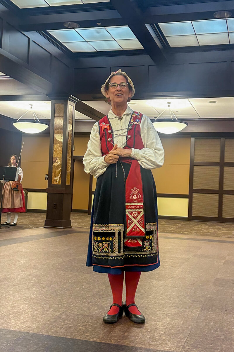 A woman in Swedish traditional dress speaking in a hall on the dance floor