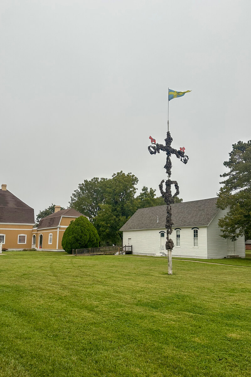 A green grassy area with a metal decorative cross flying a Swedish flag