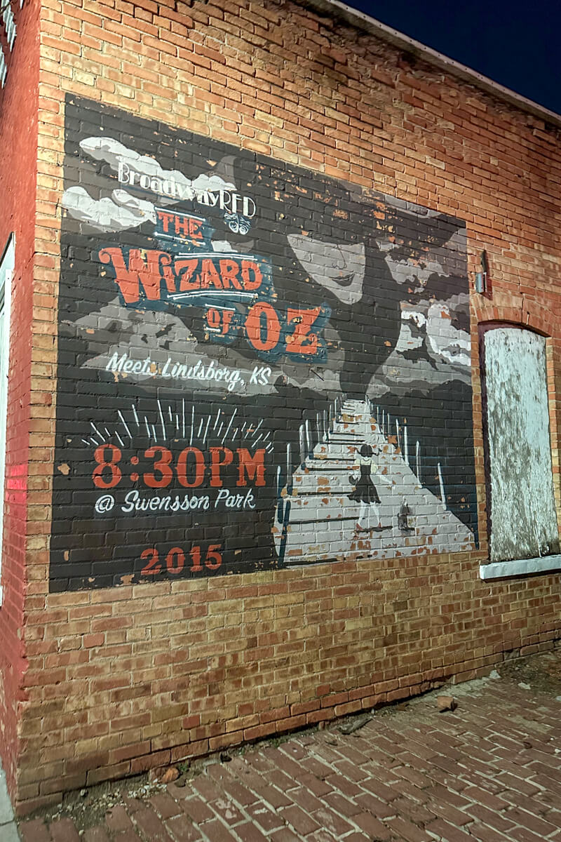 A mural on the side of a building that says "The Wizard of Oz" with the witch's head in the corner
