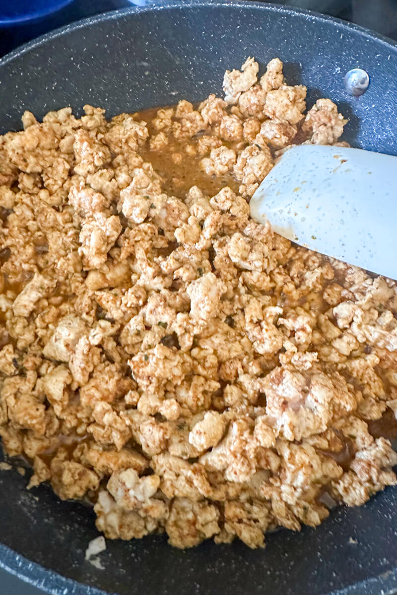 A pan cooking ground chicken taco meat