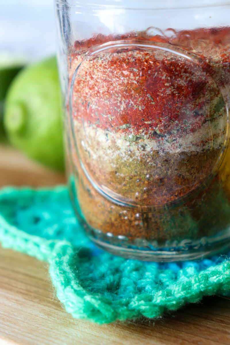 A close up of a glass Ball jar filled with keto chicken taco seasoning on a crocheted green star coaster