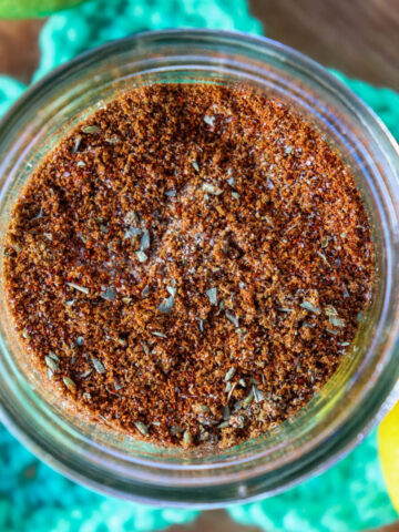 Overhead view of a glass jar of easy chicken taco seasoning on a crocheted green star coaster